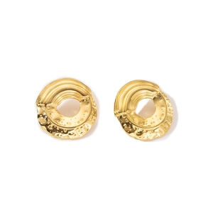 Detail of golden hollow round earrings with unique hammered texture and linear grooves