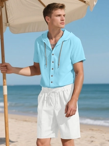 Close-up of men's linen set with blue hooded shirt and white shorts on beach