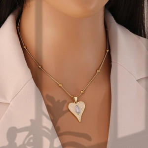 Detail of gold heart pendant with saint icon relief and zircon pavé on snake chain