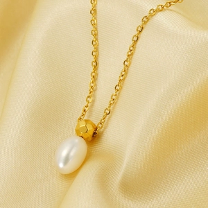 Macro detail of gold stainless steel necklace with pearl and faceted metal beads on silk