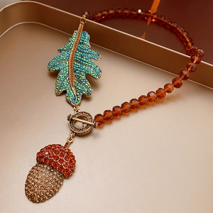 Detail of vintage necklace with crystal leaf and acorn pendants on a bronze tray