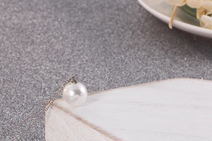 Macro d'un collier en titane argenté avec un pendentif perle blanche ronde et brillante