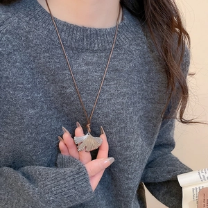 Close-up of ginkgo leaf pendant in silver finish on a brown cord necklace for women