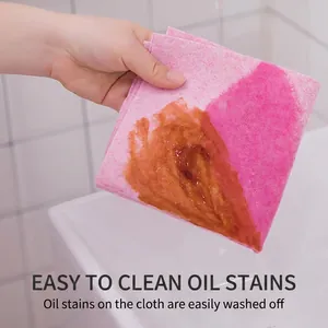 Pink coconut fiber kitchen cloth rinsing oil stains under running water in a sink