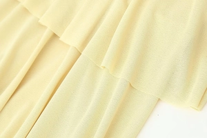 Close-up of light yellow tiered midi dress featuring fine knit texture and ruffles
