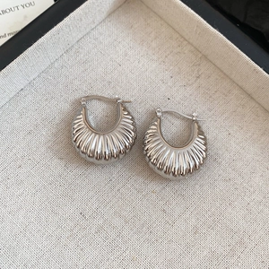 Detailed macro view of silver croissant dome earrings with polished texture