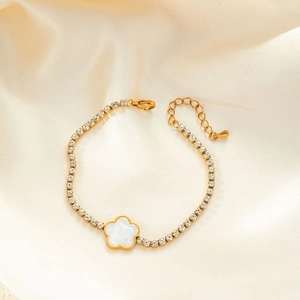 Detail of gold bracelet featuring white flower pendant and round zircon chain on silk