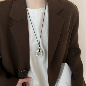 Detail of white marble pendant with silver bead on black cord necklace worn by model