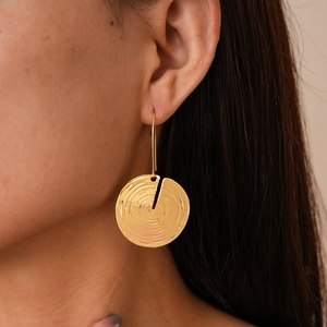 Macro detail of golden geometric hoop earring with wood grain texture and open gap design