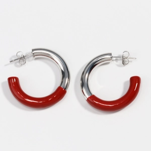 Détail de créoles en forme de C rouge et argent avec finition métallique minimaliste