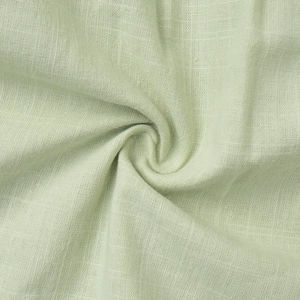 Detailed close-up of light green pleated cotton fabric with breathable weave texture