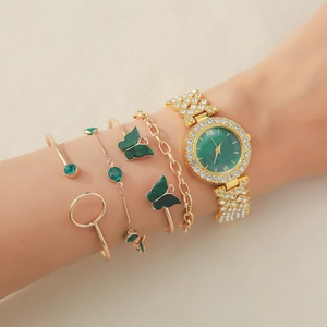 Detail of gold watch with emerald face and matching butterfly bracelet on woman wrist