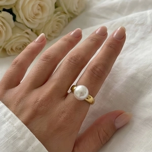 Close-up of a hand wearing a 18k gold-plated titanium ring with a large white pearl