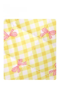 Macro shot of yellow quilted cotton fabric with pink bow prints and diamond stitching