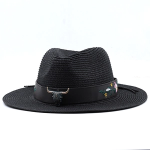 Dettaglio cappello di paglia nero con testa di toro in metallo e ricamo floreale