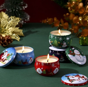 Three lit Christmas scented candles in colorful tin jars with festive holiday patterns
