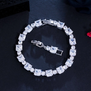 Macro detail of silver tennis bracelet with square and round zircon on black texture