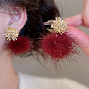Close-up of zircon snowflake studs with burgundy pompom pendants on model ear