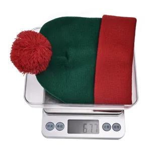 Weight measurement of 67.7g for a red and green Christmas knit hat with pompom
