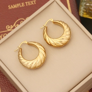 Macro detail of gold croissant hoop earrings with spiral texture in a jewelry box