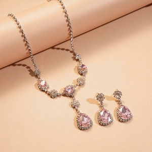 Détail de parure de bijoux avec cristal goutte rose incluant collier et boucles
