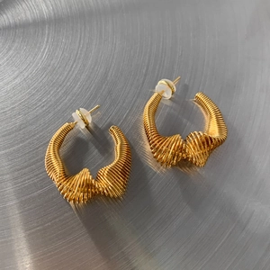 Detailed macro view of gold-plated twisted wire texture on geometric U-shaped earrings
