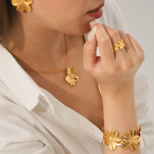 Detailed view of model wearing a gold five-petal flower jewelry set including necklace and earrings