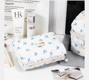 Quilted cosmetic bag with blue bow print, lace trim and pearl zipper detail