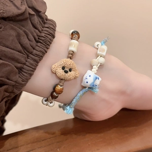 Detail of hand-woven bracelets featuring cute ceramic kitten and puppy charm beads