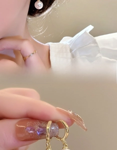 Detail shot of elegant gold wavy ring and matching pearl drop earrings for women