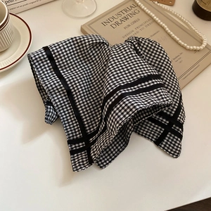 Detail of gingham checkered fabric hair tie with black ribbon edge on vintage table