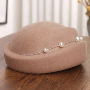 Détail de la texture d'un bibi en feutre de laine beige avec perles et strass élégants