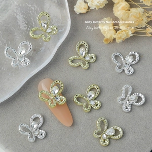 Detail of silver hollow butterfly nail jewelry with rhinestones on a nude nail tip