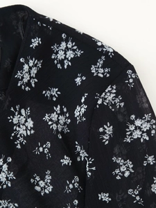 Nahaufnahme von schwarzem Chiffonstoff mit weißem Blumendruck und feinen Nähten
