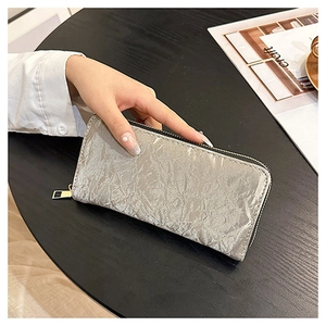 Detail of silver pleated velvet long wallet with gold zipper in a lifestyle setting