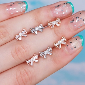 Detailed close-up of zircon bow stud earrings in gold, silver, and rose gold finishes