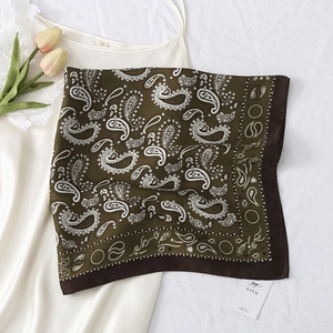 Detailed macro view of a vintage paisley square silk scarf on a white dress with tulips