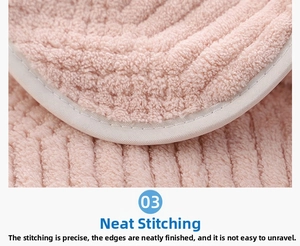 Close-up of the reinforced stitching and thick pink coral fleece texture of the bath towel