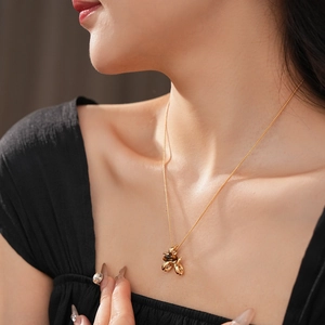 Detailed view of a gold-plated bee pendant necklace with tiger eye stone on a female model