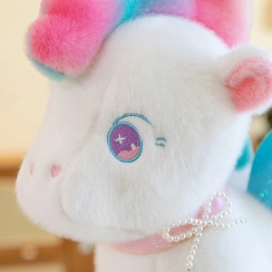 Cute white unicorn plush toy with rainbow mane and pearl necklace close-up view