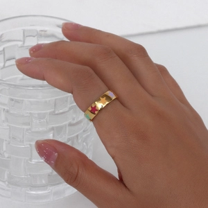 Close-up of golden 18K plated ring featuring colorful star patterns on hand
