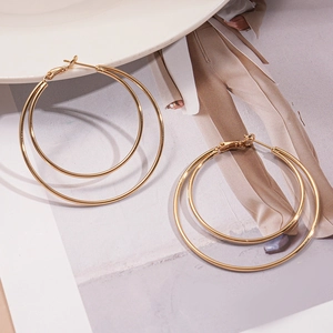 Detailed view of layered geometric golden double hoop earrings on a fashion magazine background