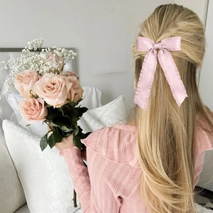 Detailed view of pink satin bow hair clip with ruffle edges and long elegant ribbon