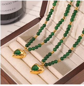 Détail du pendentif cœur avec zircon vert et perles dorées sur une boîte à bijoux en bois