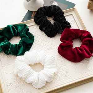 Detail of velvet and pleated scrunchies in burgundy, green, black and white on a tray
