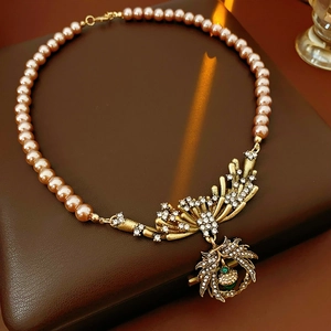 Detail of vintage necklace with pink pearls and a golden rhinestone pineapple pendant