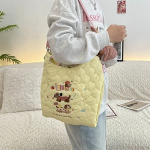 Detail of quilted tote bag featuring cute cartoon dog embroidery and pink straps