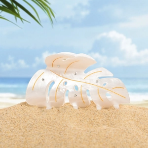 Pince à cheveux feuille de monstera en acétate blanc perle et strass sur la plage