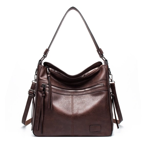 Detail of vintage brown PU leather shoulder bag with zipper pockets and tassel