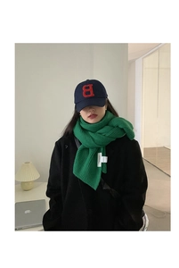 Detail of emerald green ribbed knit scarf paired with a navy blue embroidered baseball cap